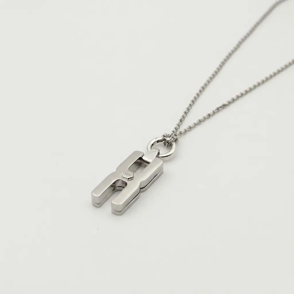 Gros plan du fermoir et de la chaîne maille forçat du pendentif Hera R en argent rhodié, finition artisanale française Alhiage