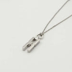 Gros plan du fermoir et de la chaîne maille forçat du pendentif Hera R en argent rhodié, finition artisanale française Alhiage