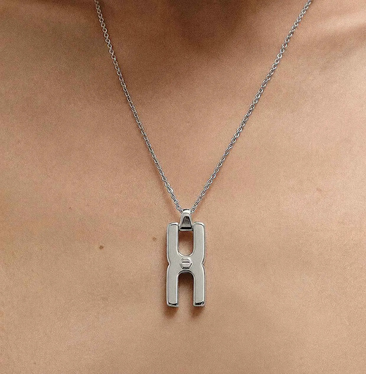 Gros plan du fermoir et de la chaîne maille forçat du pendentif Hera R en argent rhodié, finition artisanale française Alhiage