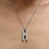 Gros plan du fermoir et de la chaîne maille forçat du pendentif Hera R en argent rhodié, finition artisanale française Alhiage