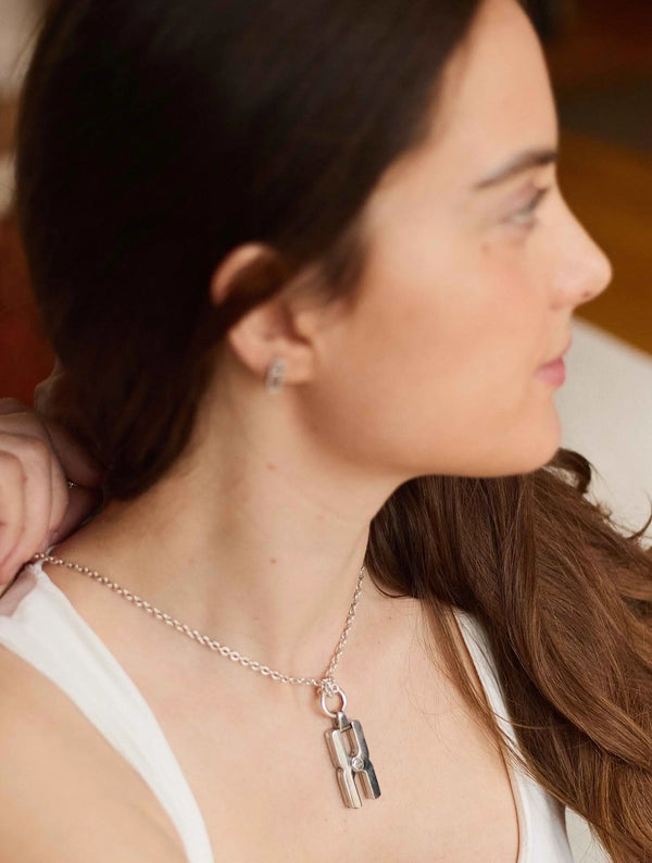 Gros plan du fermoir et de la chaîne maille forçat du pendentif Hera R en argent rhodié, finition artisanale française Alhiage